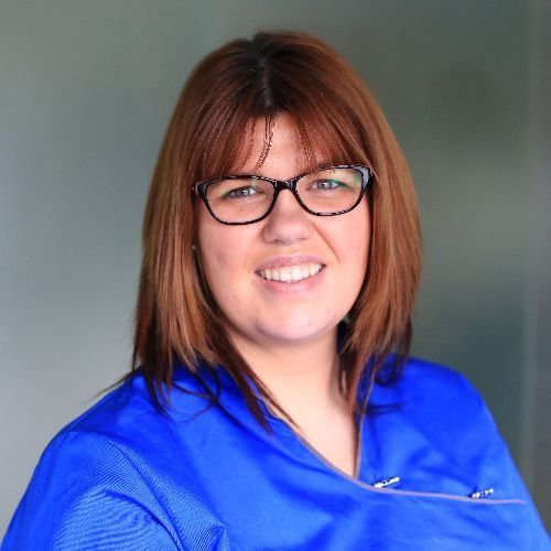 Una mujer que lleva gafas y una camisa azul sonríe para la cámara.
