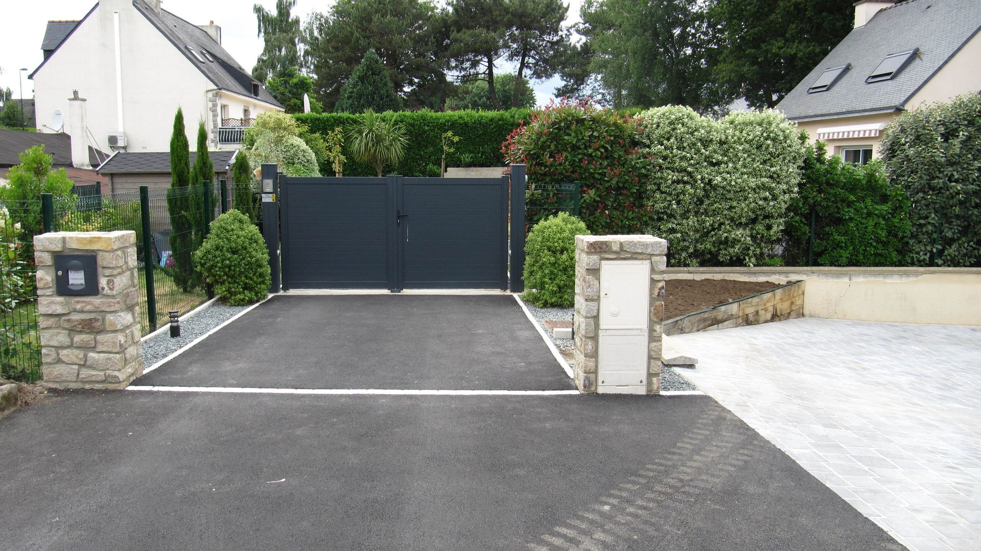 Chemin d'accès en béton devant un portail gris foncé