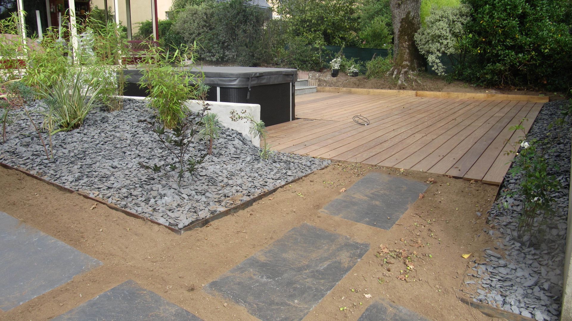 Chemin en dalles vers une terrasse en bois et un bain à remous