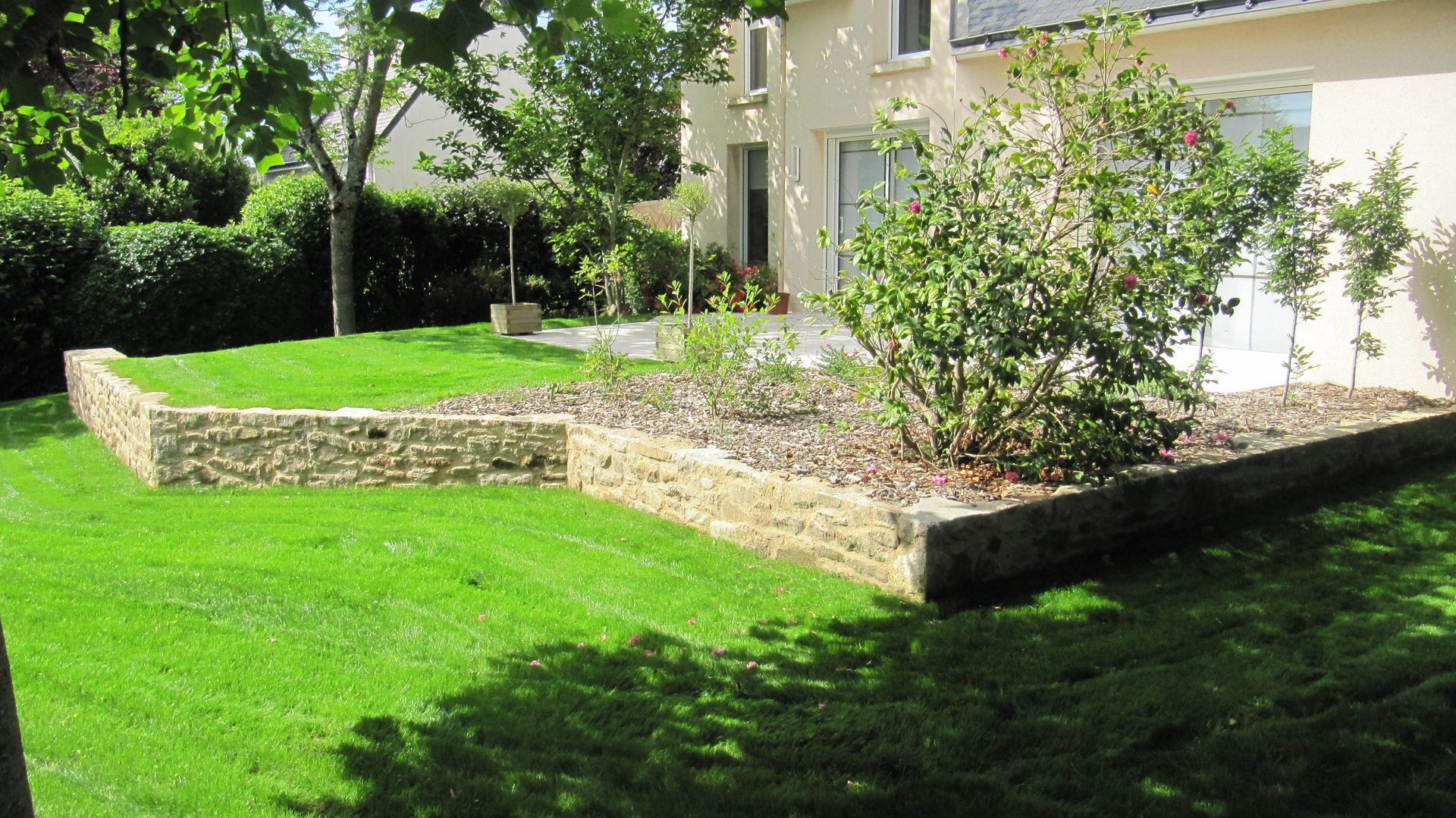 Jardin rehaussé d'un muret décoré de massifs