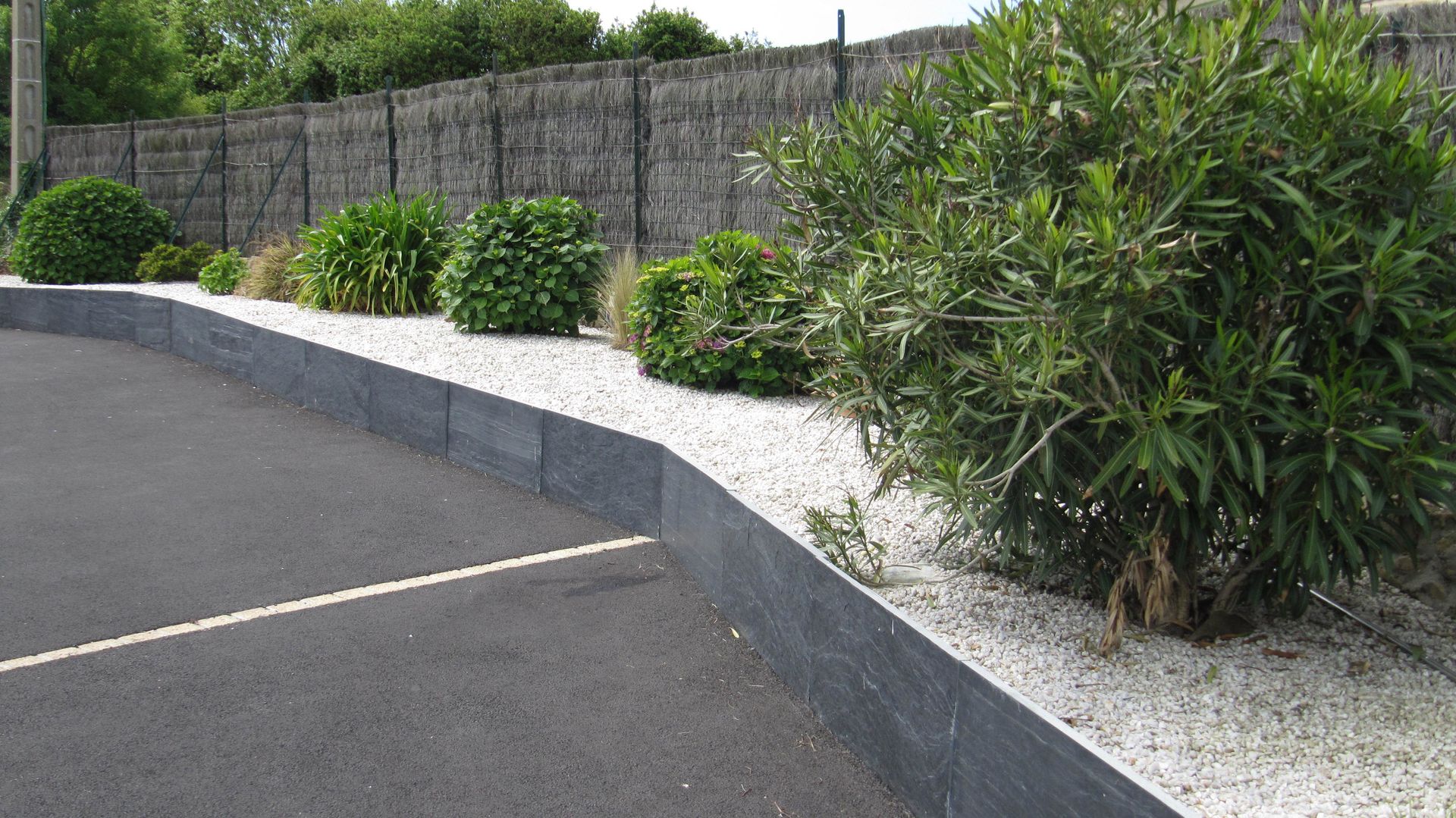 Voie d'accès en béton bordée de massifs