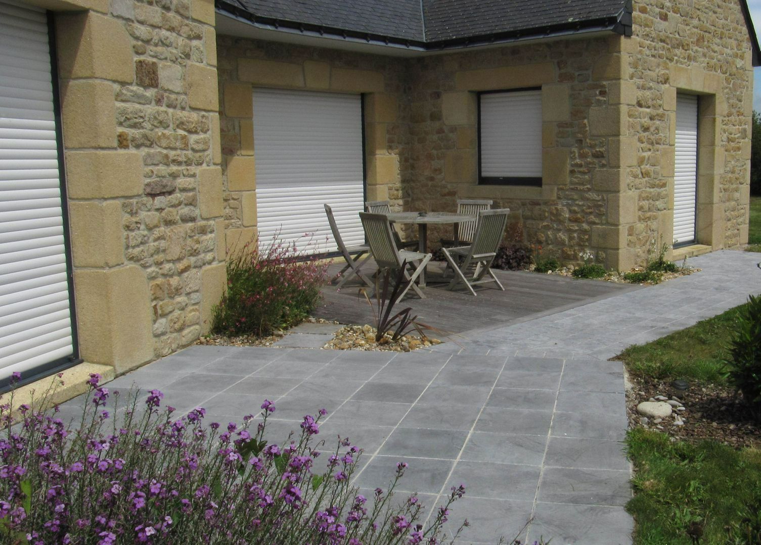 Salon de jardin sur une terrasse en pierre devant une maison bretonne