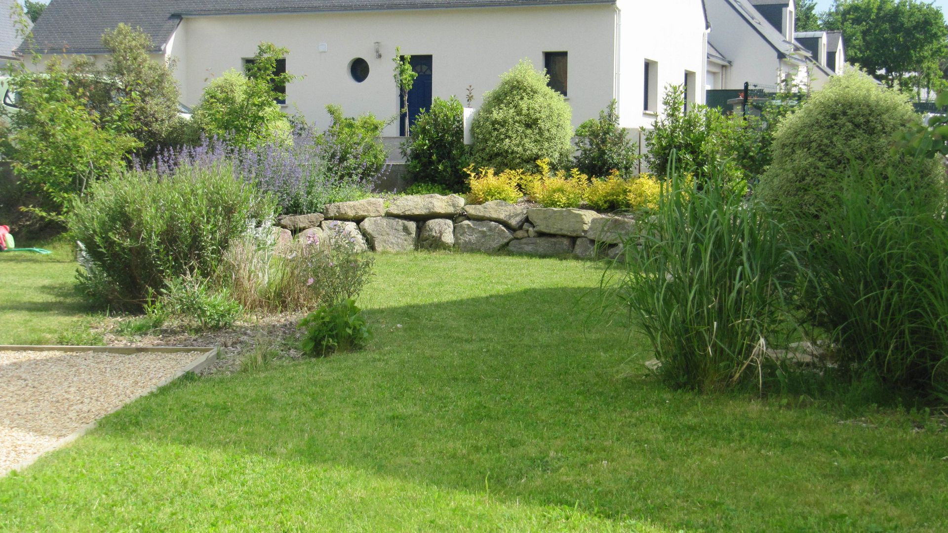 Jardin arrangé de massifs et murs en pierres