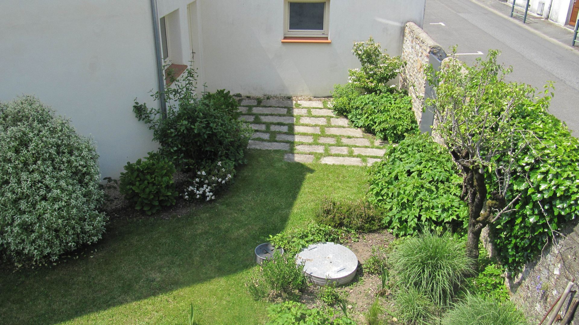 Une cour pavée avec de l'herbe et des buissons