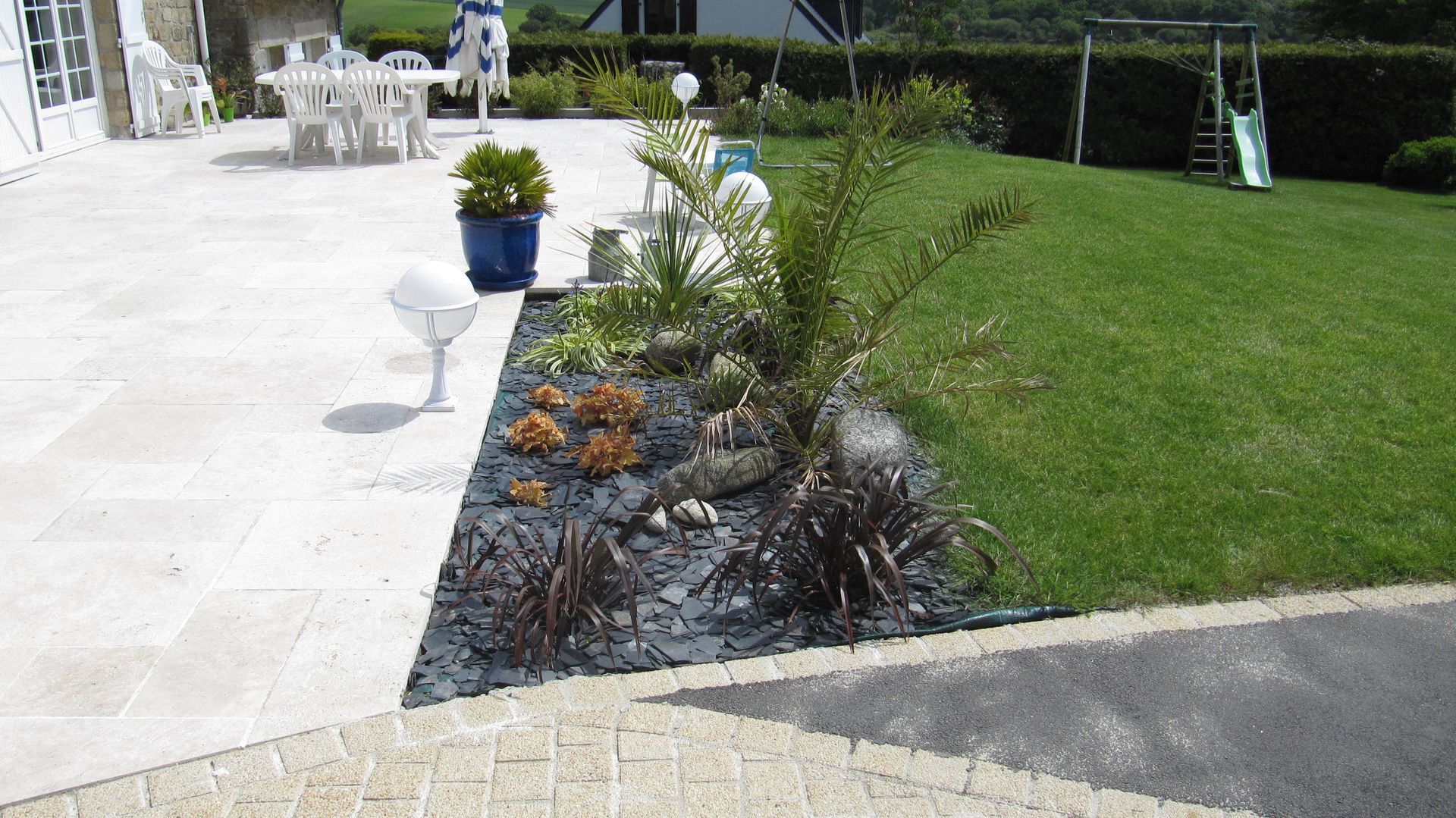 Une jardinière entre une terrasse en pierre et du gazon