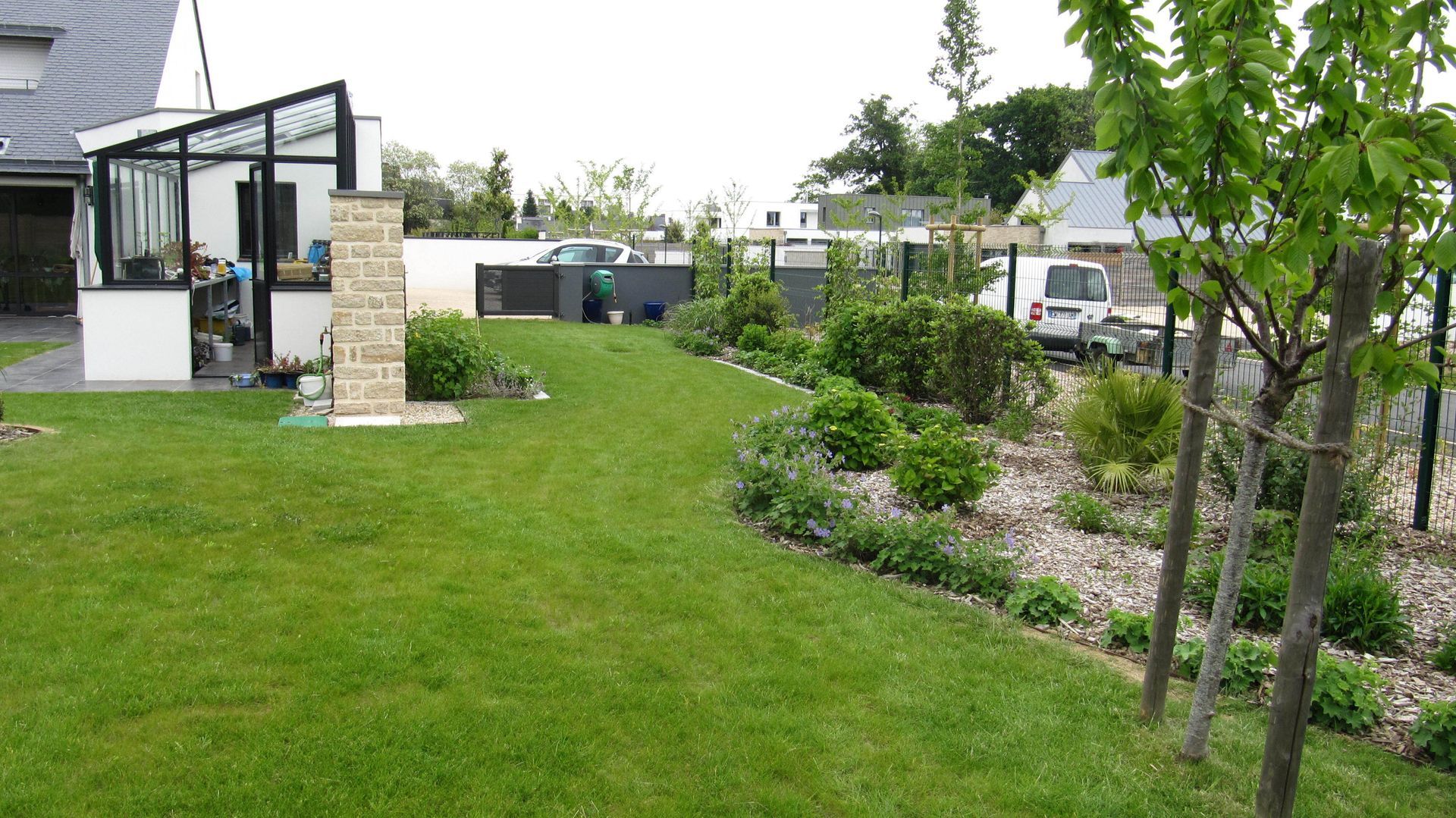 Jardin avec une véranda, du gazon et de jeunes arbres