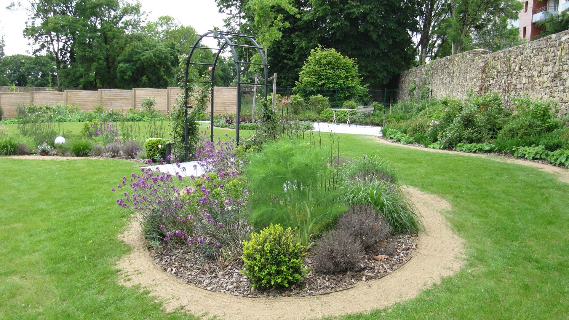 Un massif rond devant une arche au milieu de la pelouse