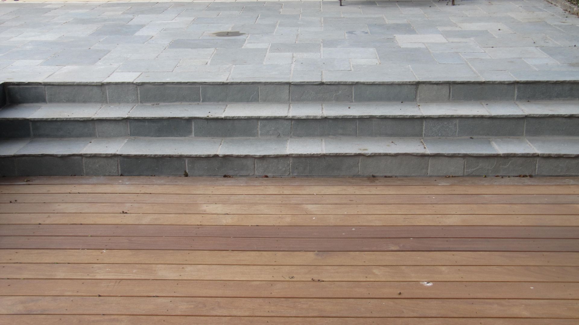 Terrasse en bois et 3 marches vers une terrasse en pavés