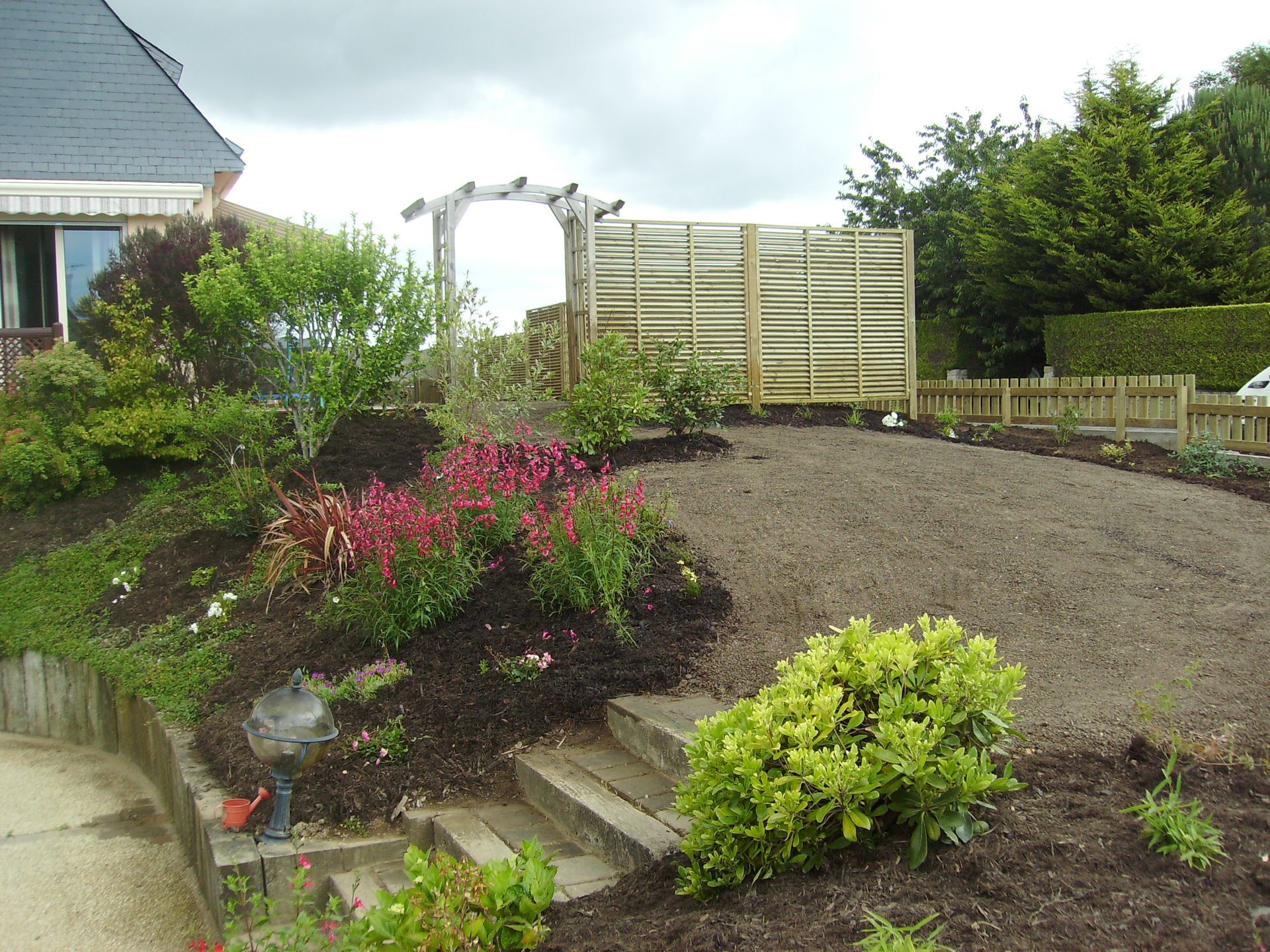 Massif et marches devant un chemin en terre et arche en bois
