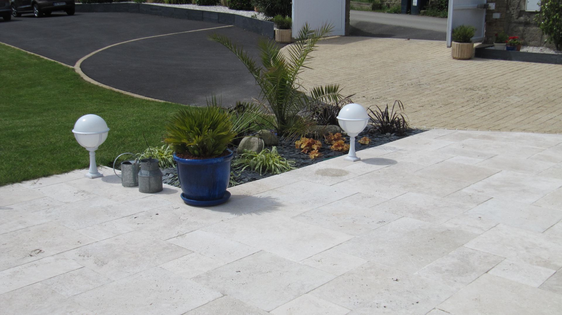 Une terrasse en pierres blanches avec un petit massif