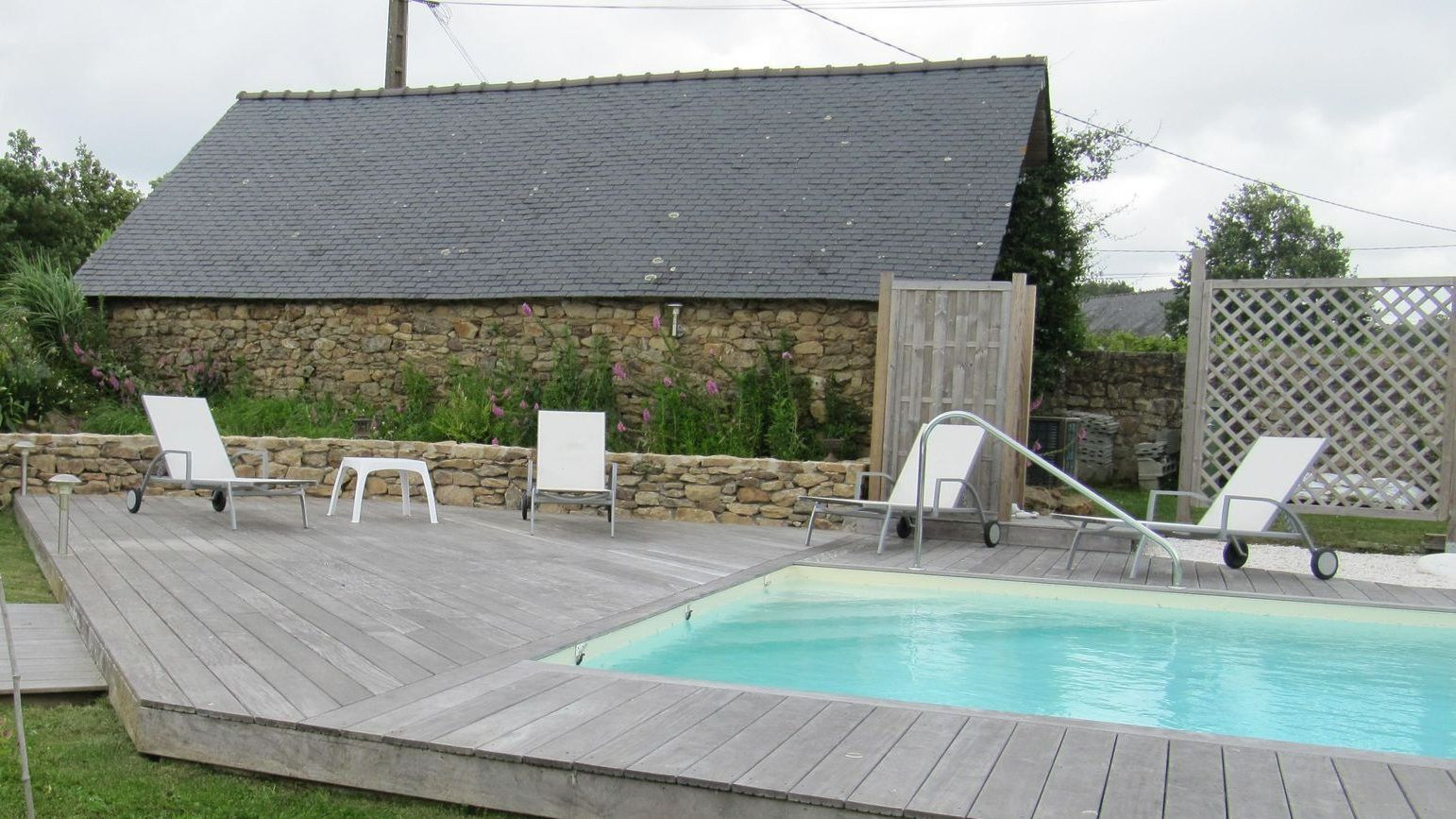 Une terrasse en bois avec une piscine et des transats