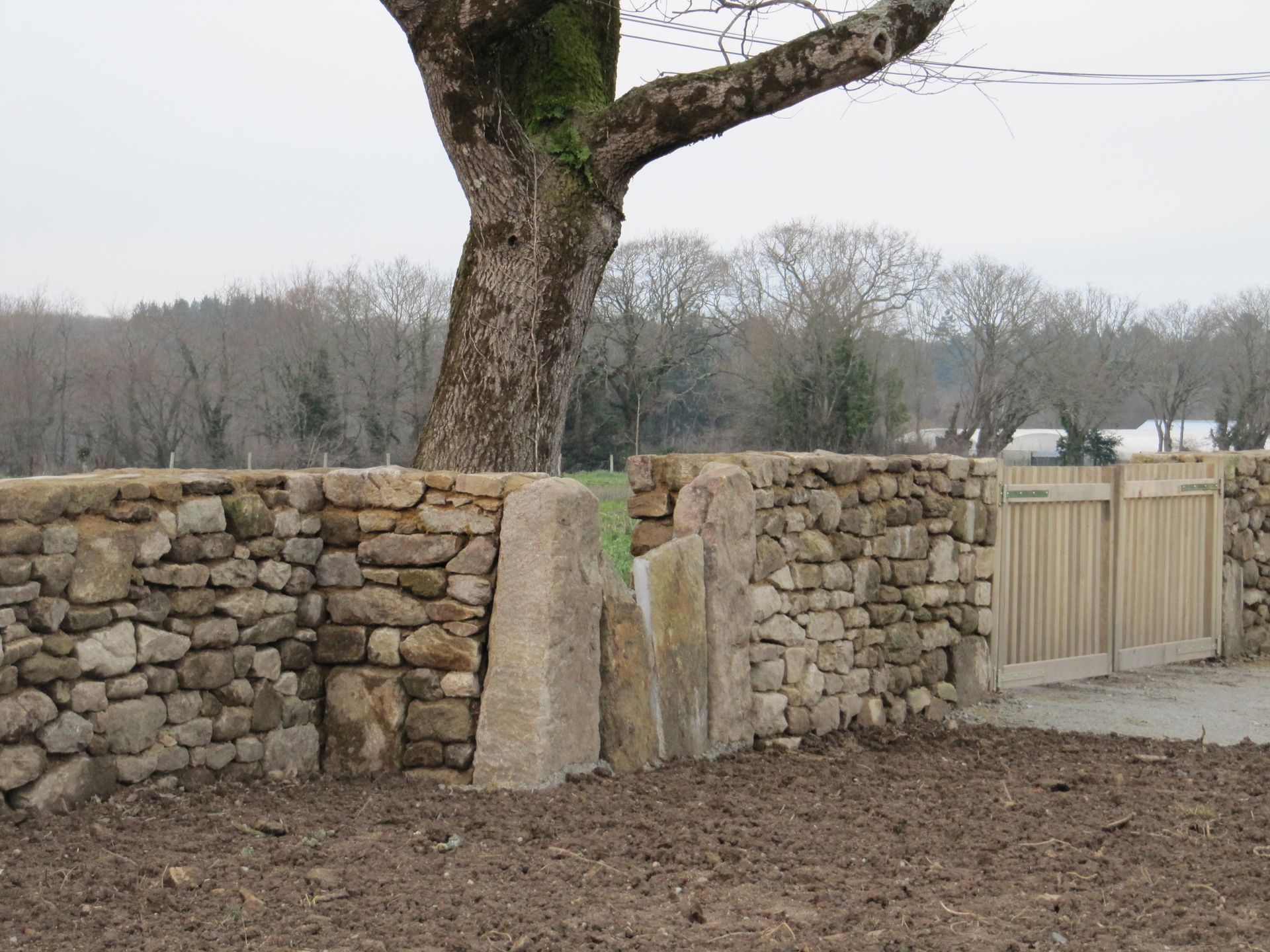Un mur en pierres sèches et portail en bois