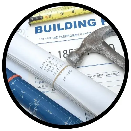 Planos de construcción, martillo y cinta métrica sobre una mesa.