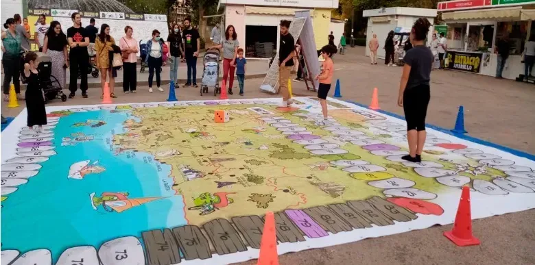 La gente se reunió alrededor de un gran mapa de calles colorido extendido en el suelo con conos naranjas cerca.