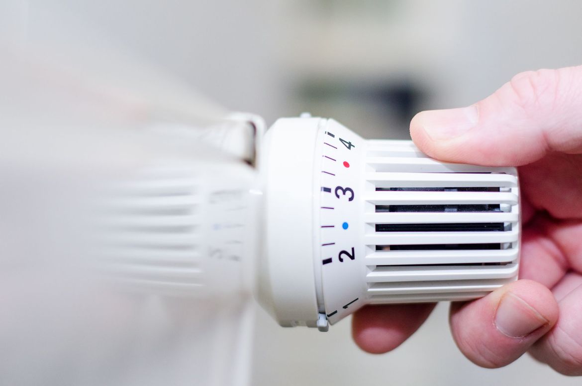 Réglage manuel du thermostat d'un radiateur blanc, en l'augmentant pour accroître la chaleur.
