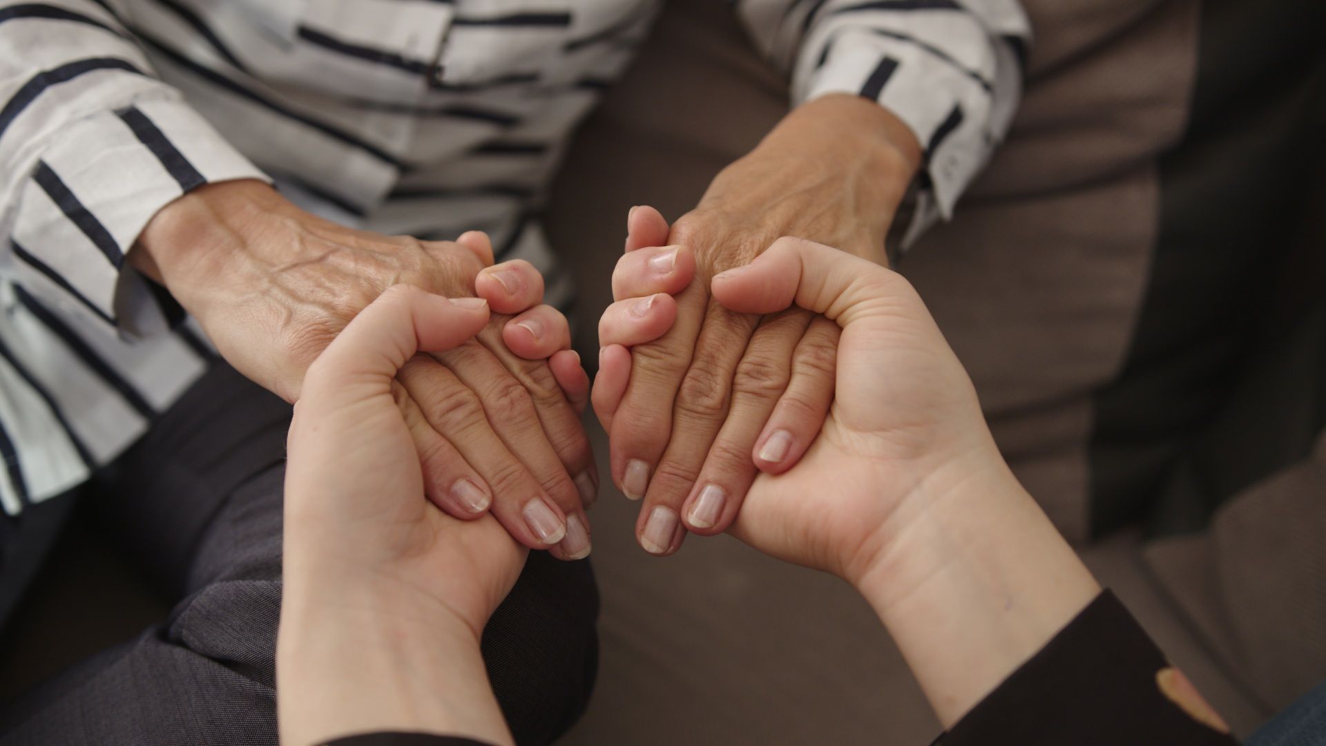 Eine junge Frau hält die Hände einer älteren Frau.