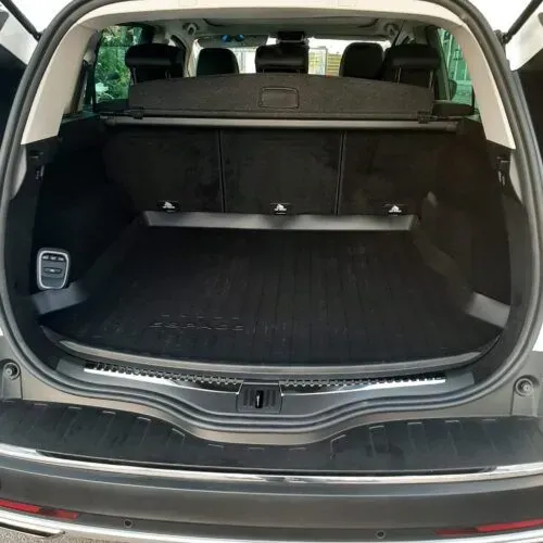 El maletero de un coche con la puerta abierta y una bandeja en el suelo.