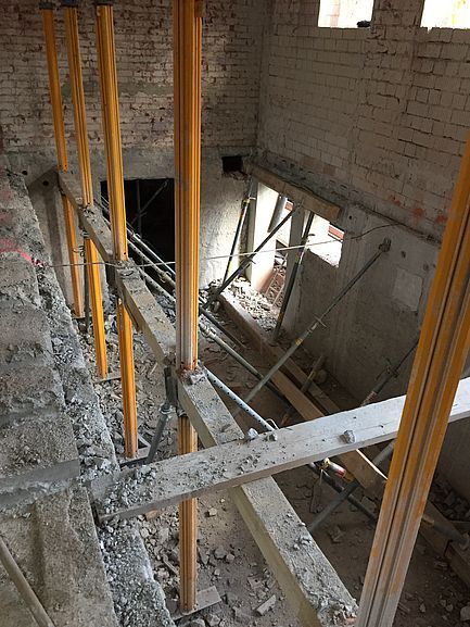 Innenbaustelle mit Gerüst und Holzstützen in einer gemauerten Treppenhausöffnung