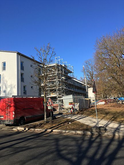 Moderne Apartmentgebäude im Bau neben einer Straße, ein roter Lieferwagen und strahlend blauer Himmel