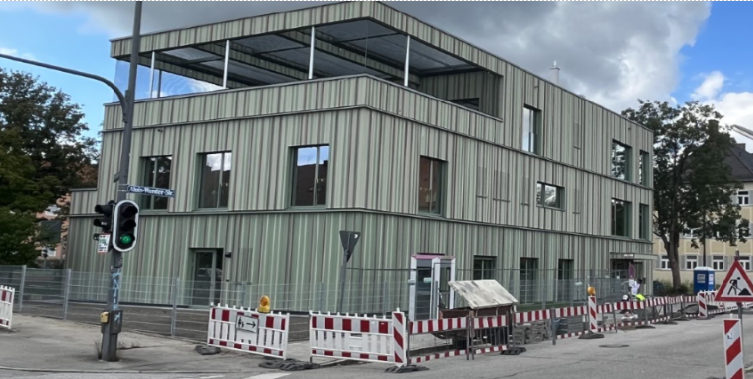 Modernes mehrstöckiges Gebäude mit farbenfrohen vertikalen Paneelen an einer sonnigen Straßenecke