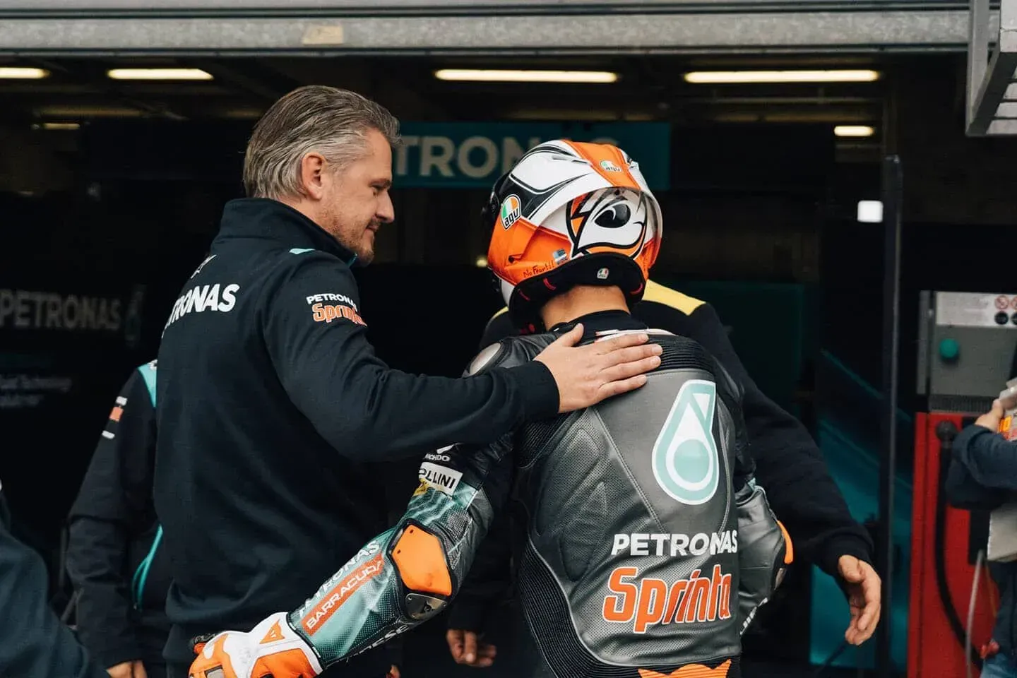 Um homem está abraçando um motociclista em uma garagem.