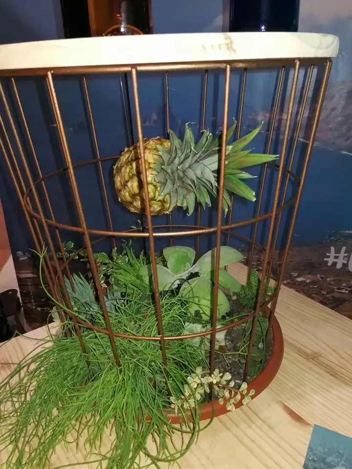 Hortensias con flores blancas, azules y violetas entre follaje verde, junto a un patio de ladrillo rojo.