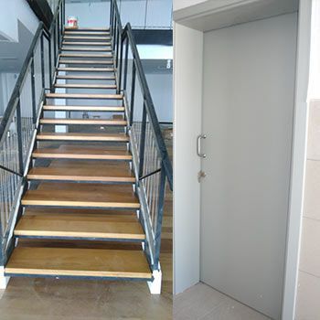 Una escalera con escalones de madera y una barandilla de metal junto a una puerta.