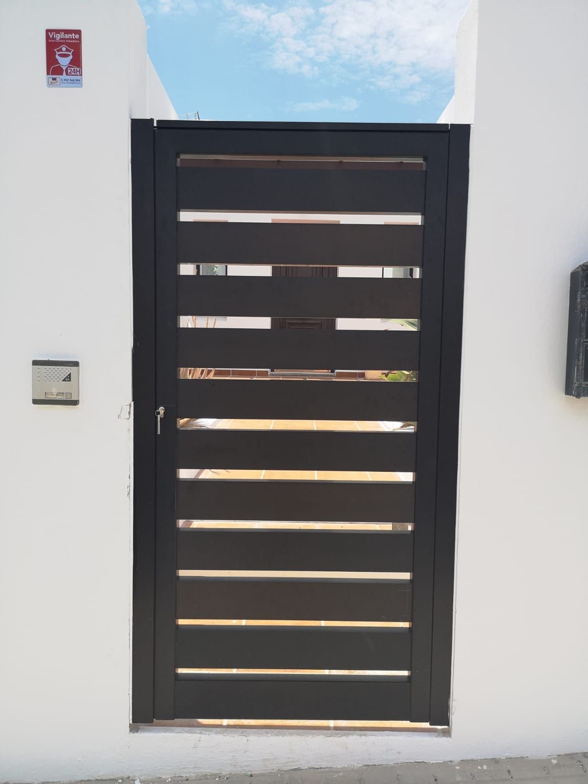 Una pared blanca con una puerta negra y un buzón.