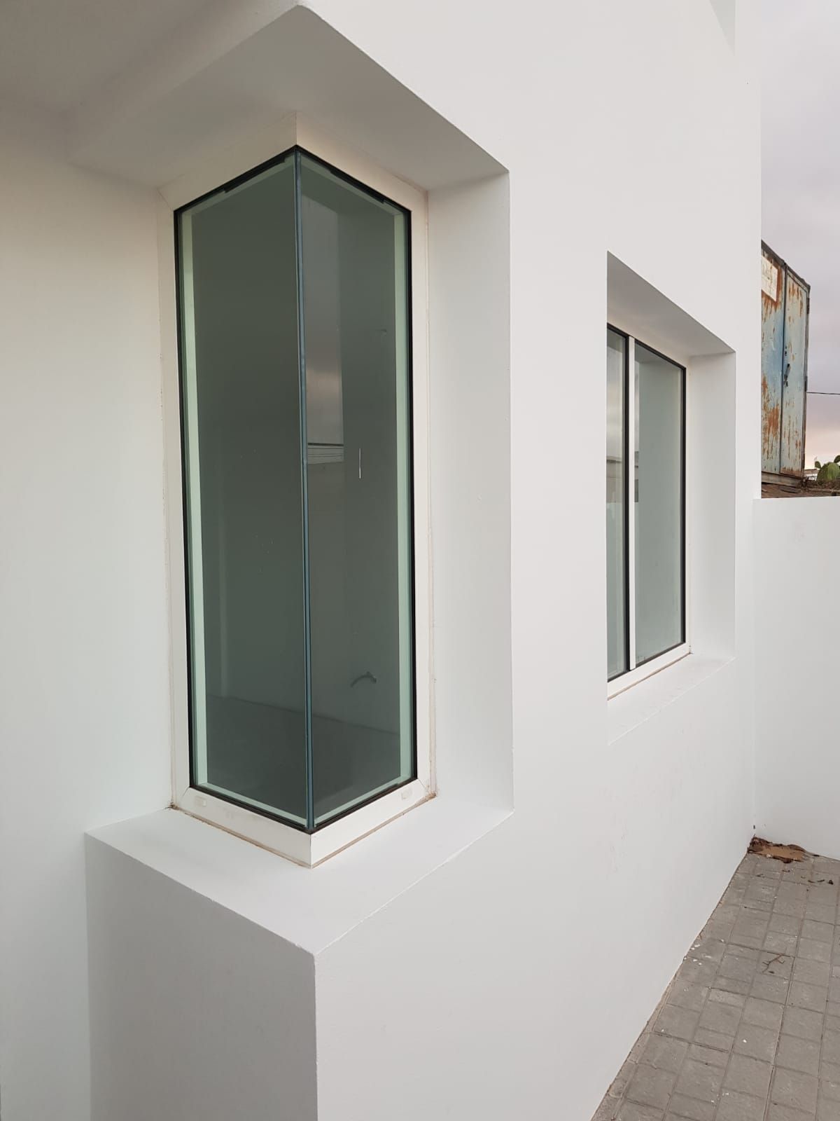 Una pared blanca con dos ventanas.