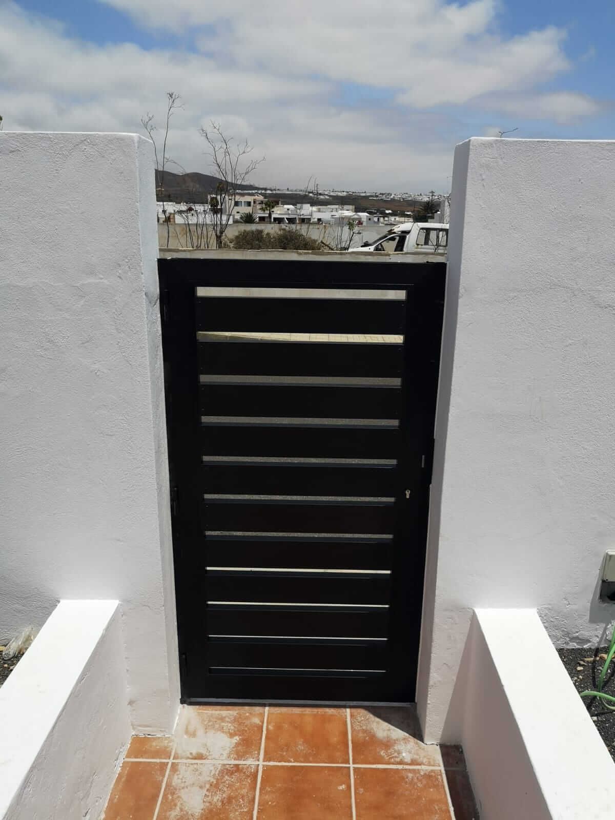 Una puerta negra está entre dos paredes blancas.