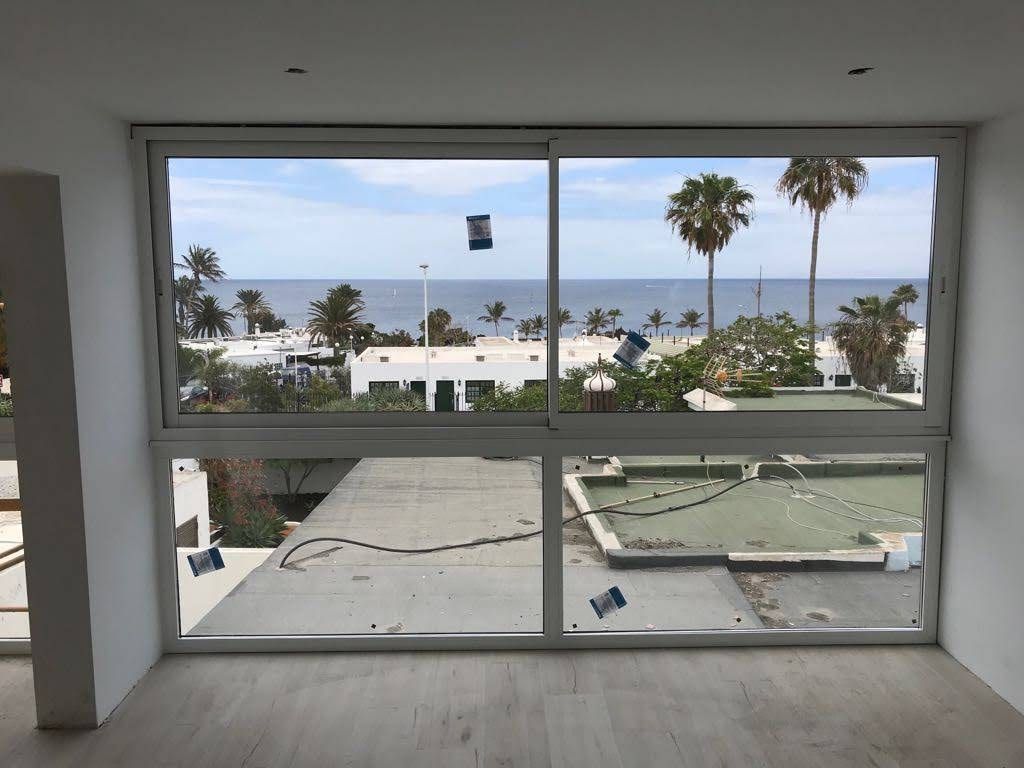 Una gran ventana con vista al mar y palmeras.