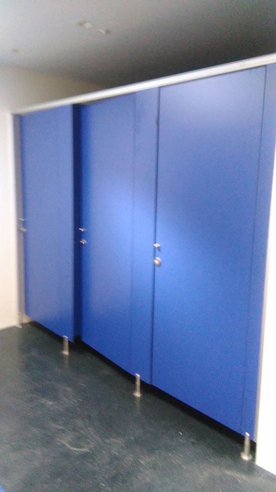 Una fila de cubículos de baño azules en un baño.