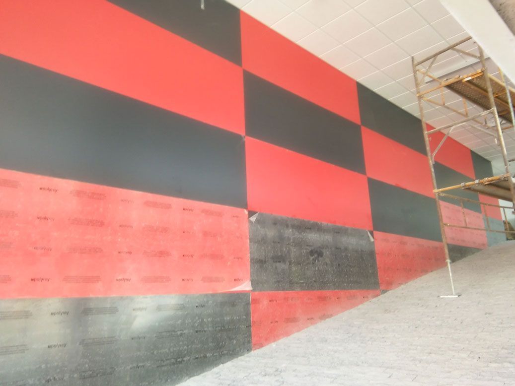 Una pared roja y negra con un andamio al fondo