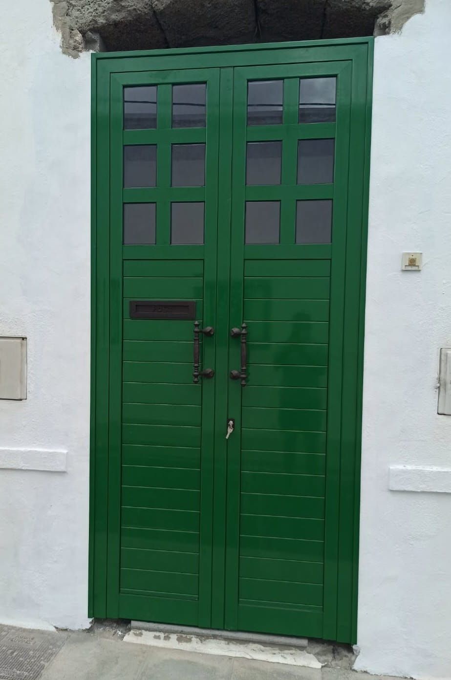Una puerta verde está sentada sobre una pared blanca.