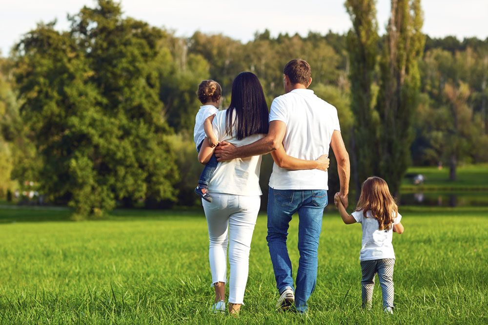 Famille de 4 personnes marchant dans l'herbe