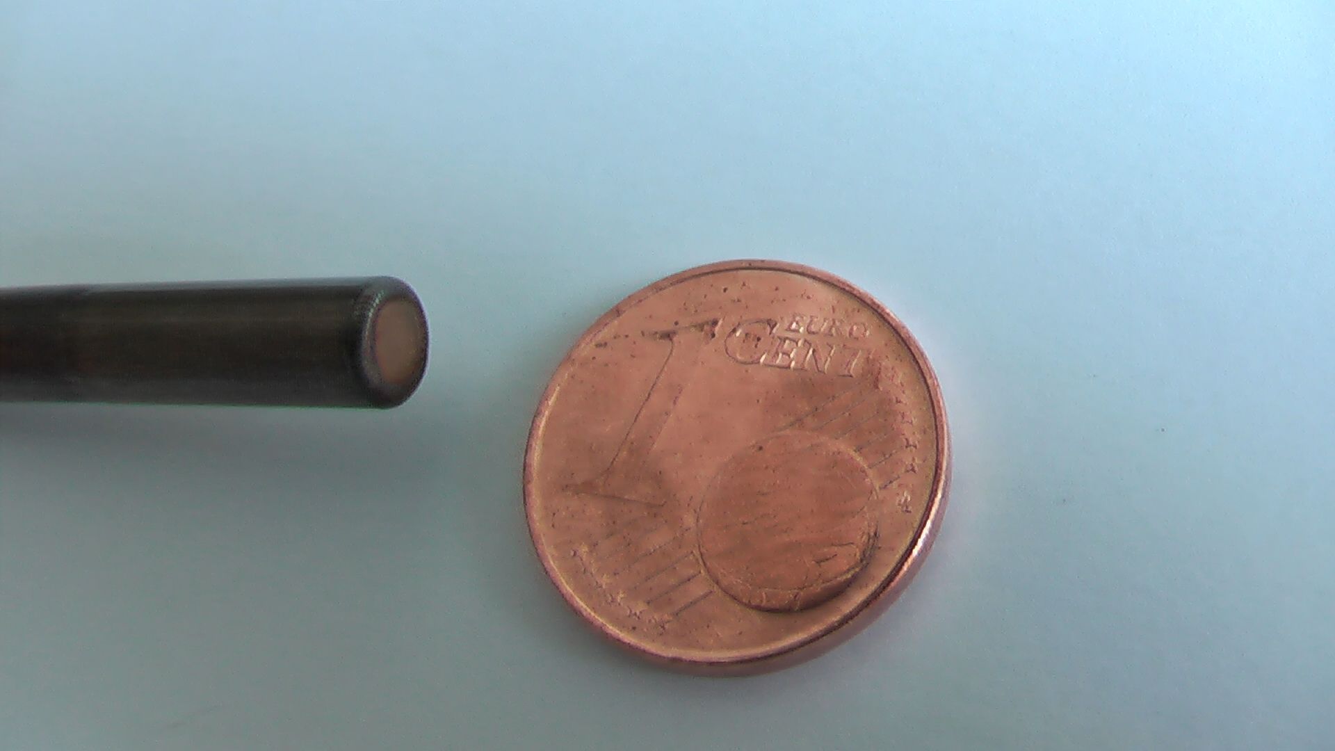 Ein Penny liegt neben einer Stange auf einem Tisch, um das Laserschweißen zu demonstrieren.