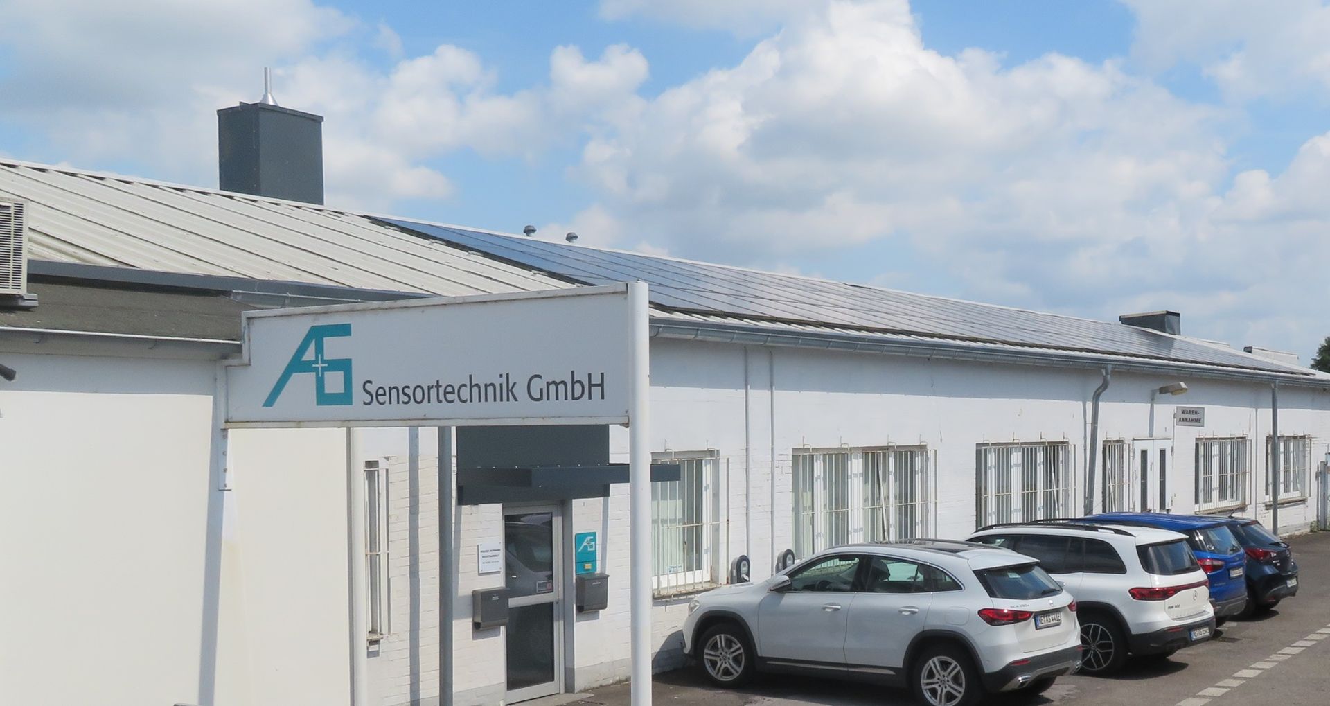 A row of cars are parked in front of a building.
