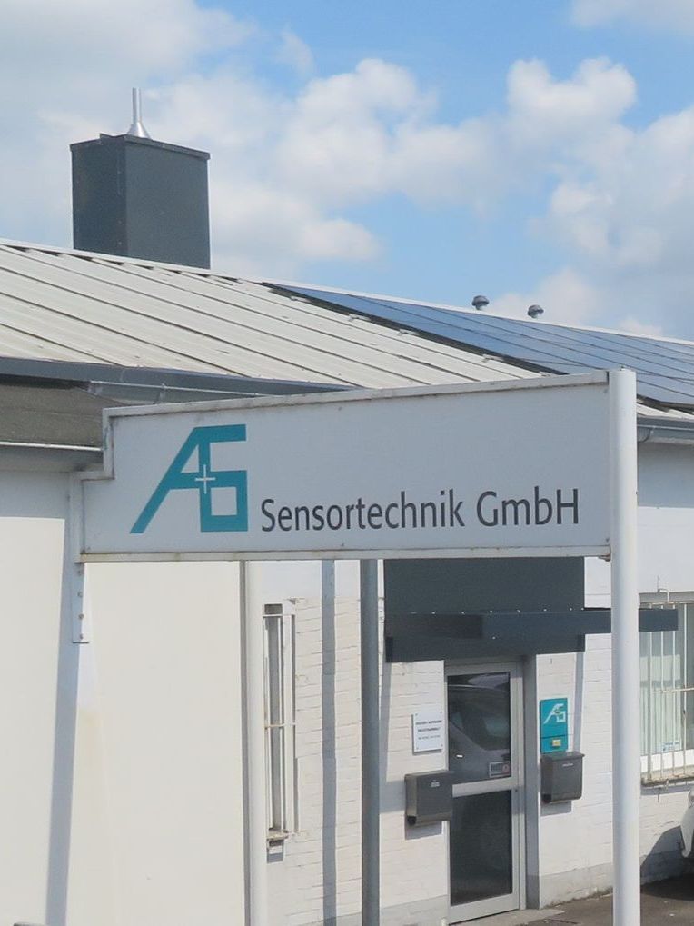 Ein weißes Gebäude mit einem Schild mit der Aufschrift „A+S Sensortechnik GmbH“