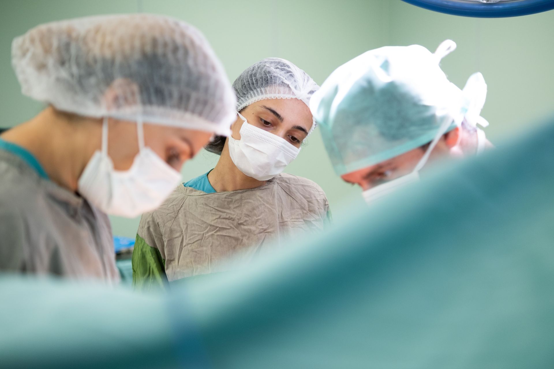 Surgeons in masks and caps working together in an operating room