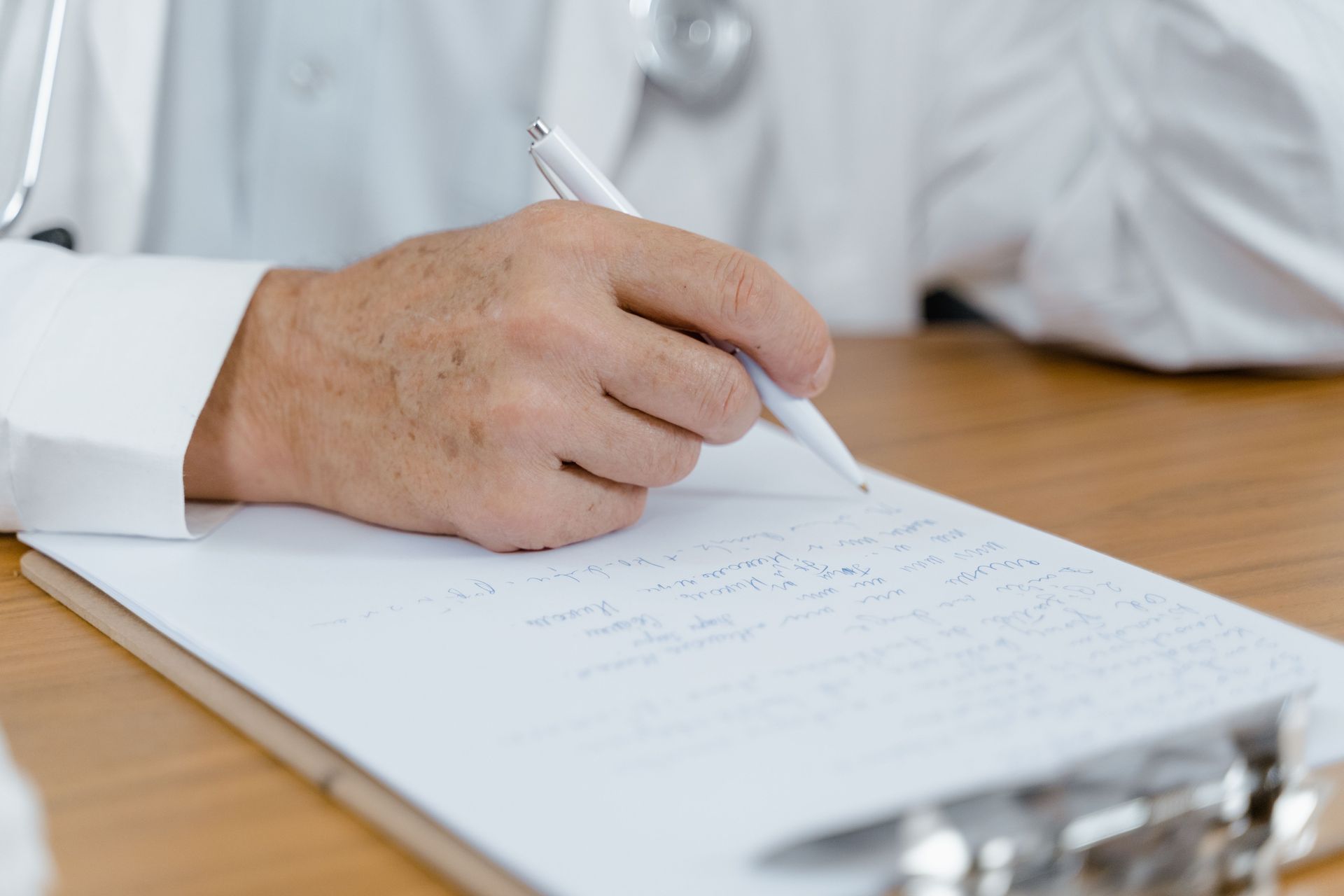 Doctor’s hand writing on a clipboard during a medical exam