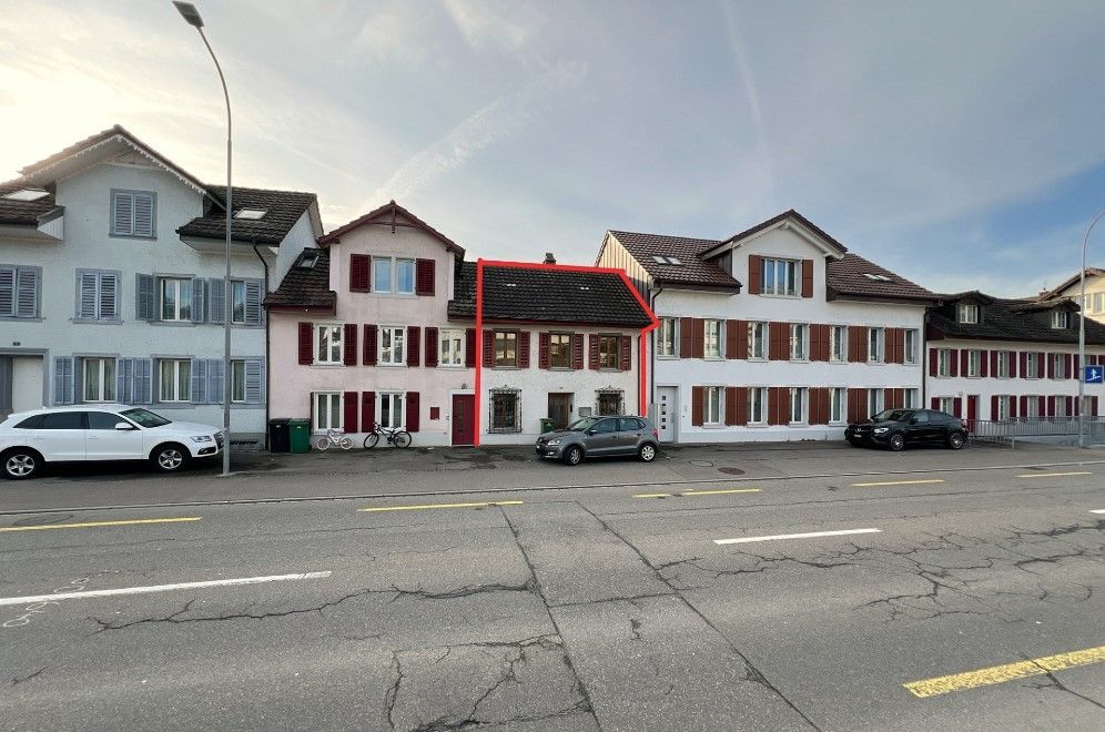 Eine Reihe von Gebäuden, vor denen Autos geparkt sind.