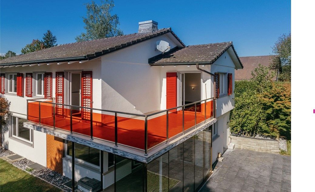 Ein weißes Haus mit roten Fensterläden und einem Balkon.