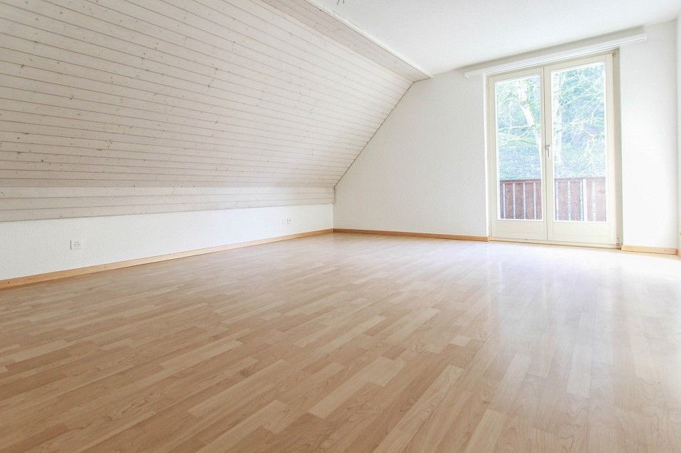 Ein leerer Raum mit Hartholzböden und einem Balkon.