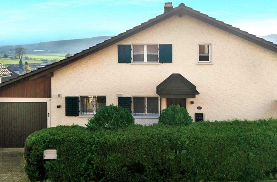 Ein weißes Haus mit einer grünen Hecke davor