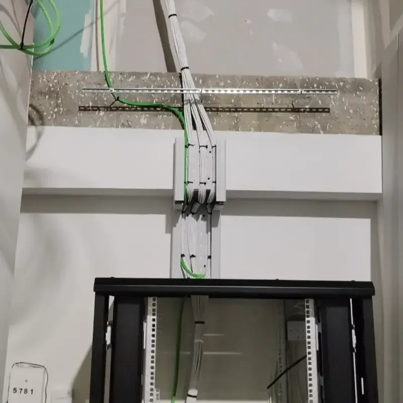 Empalmes de cables montados en la pared y cableado blanco sobre un rack de servidores negro en un cuarto de servicio.