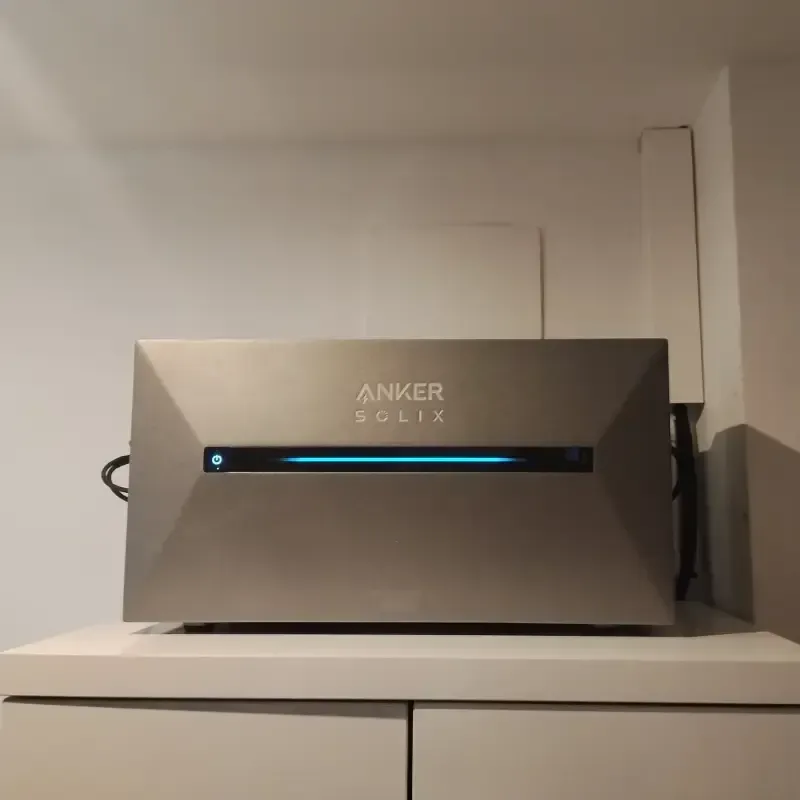 Unidad de baterías Anker SOLIX en un estante blanco con luz indicadora azul.