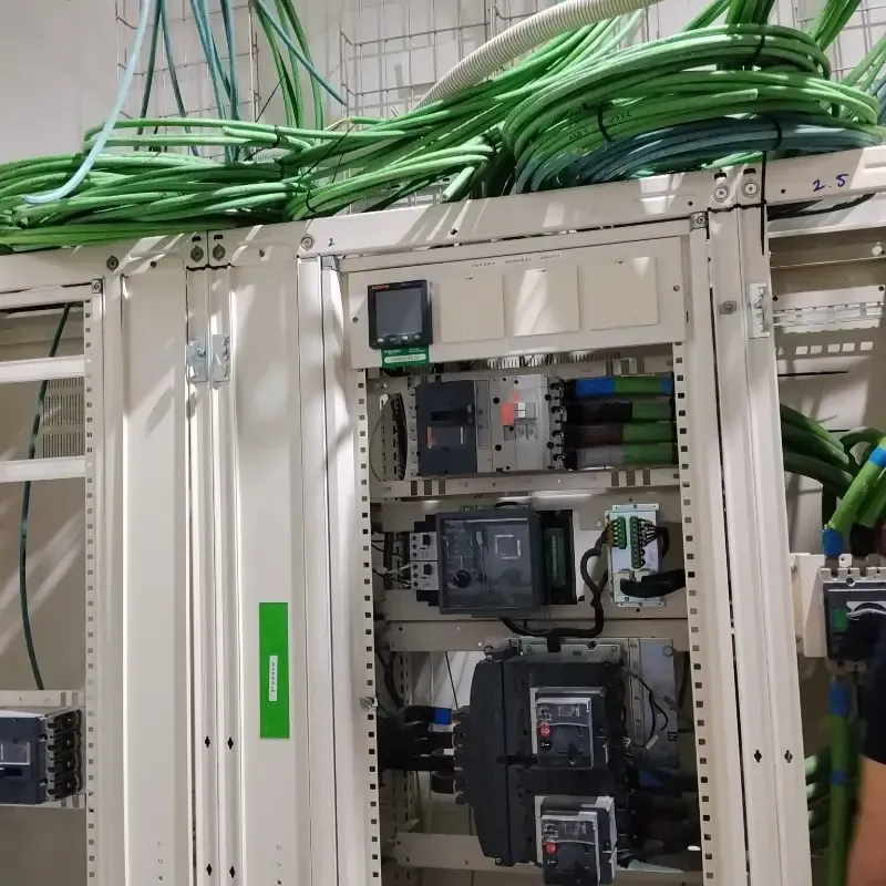Armario de control eléctrico con cables verdes y componentes de circuito dentro de un panel industrial.
