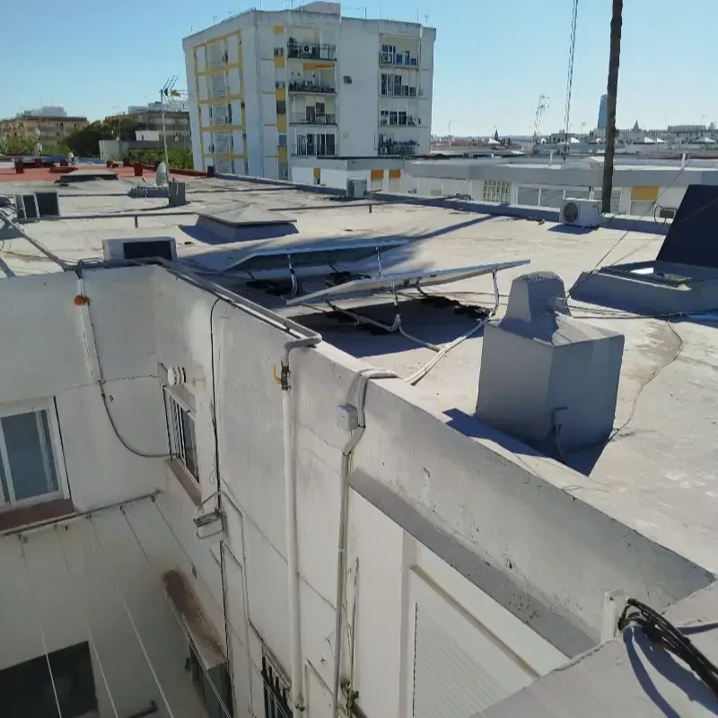 Azotea con paneles solares y un pequeño cerramiento en la azotea de un edificio soleado en la ciudad.
