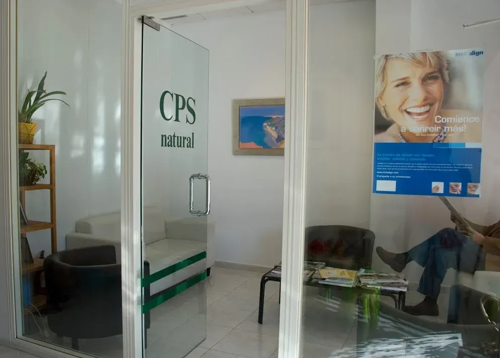 Entrada a un consultorio dental con sala de espera. La puerta de cristal dice