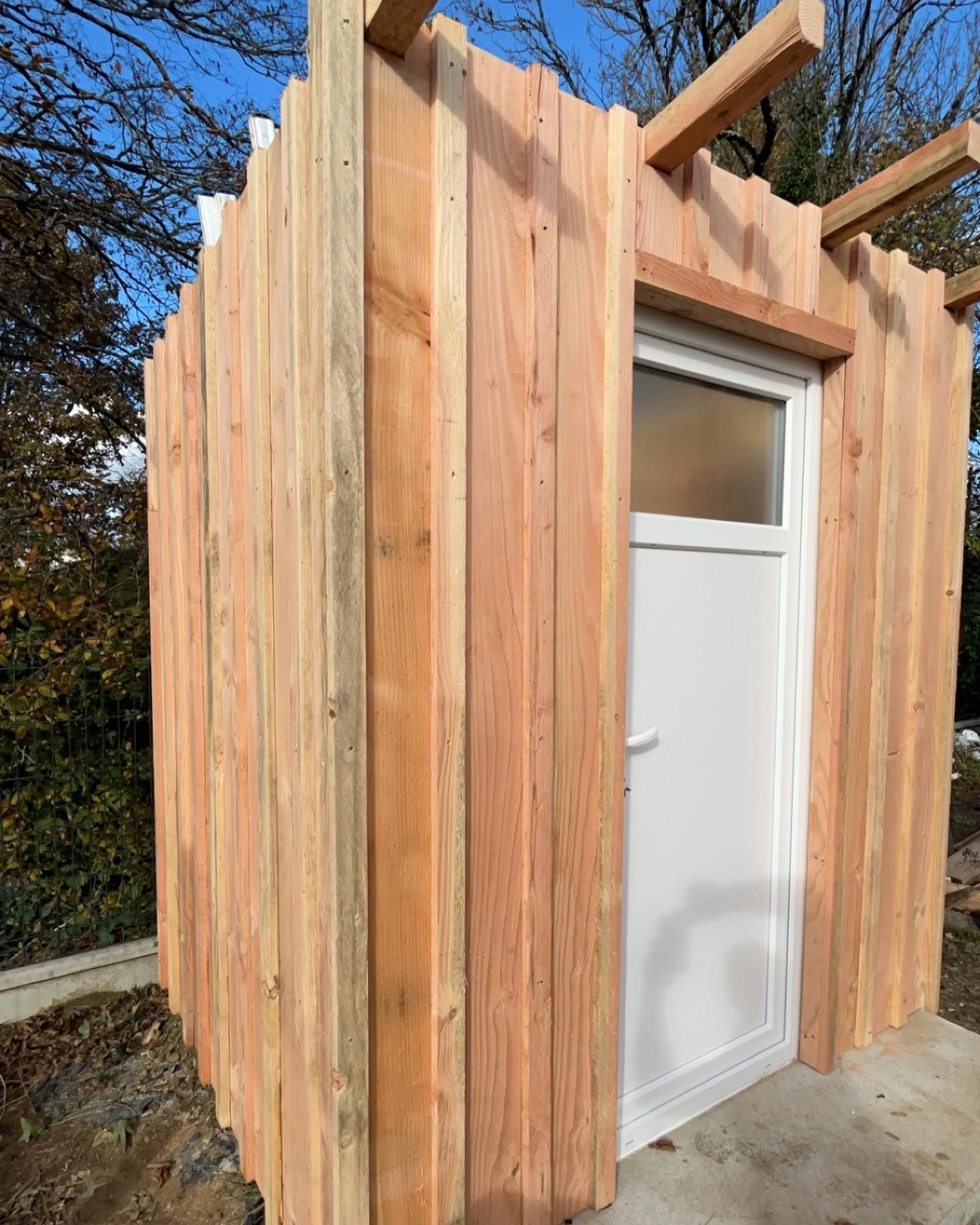 Construction en cours d'un abri de jardin en bois avec une porte en PVC blanche